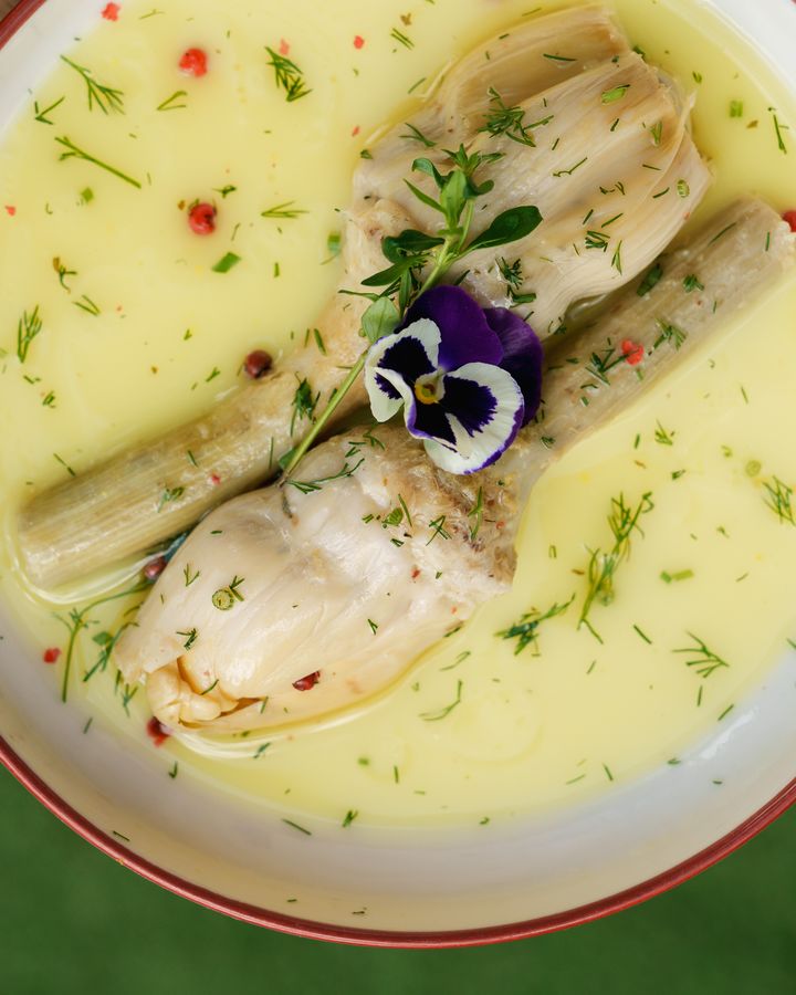 Yukarıdan sarı soslu bir tabak, dereotu ve mor yenilebilir çiçekle