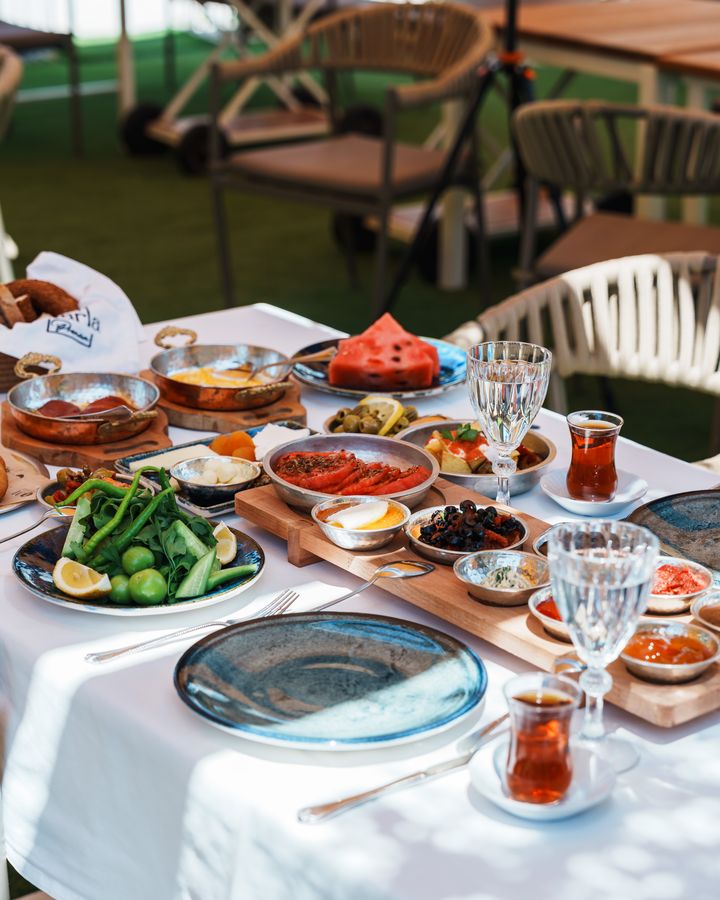 Bahçede kurulu kahvaltı masası: çay bardakları, küçük kâseler ve tabaklar