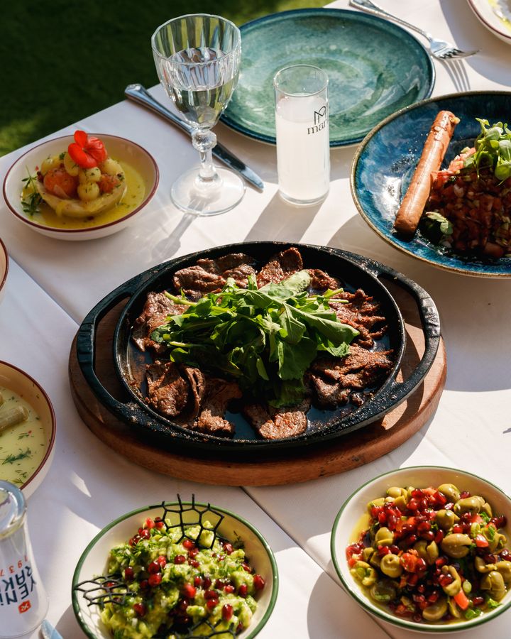 Masada sıcak tabakta et ve yanında meze kâseleri