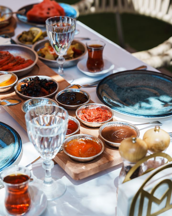 Bahçede serpme kahvaltı: küçük kâselerde reçeller, peynirler, karpuz ve çay