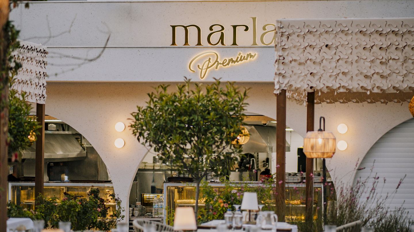 Marla Premium cephesi: altın renkli tabela, kemerli bölüm ve önünde kurulu masalar